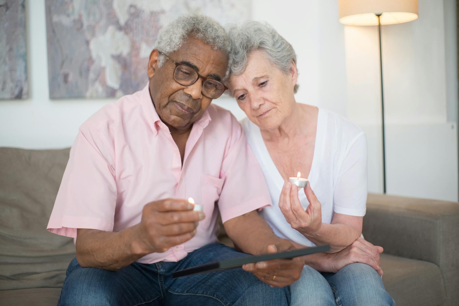 elderly man in pink button up shirt holding a candle with elderly woman in white v neck t shirt